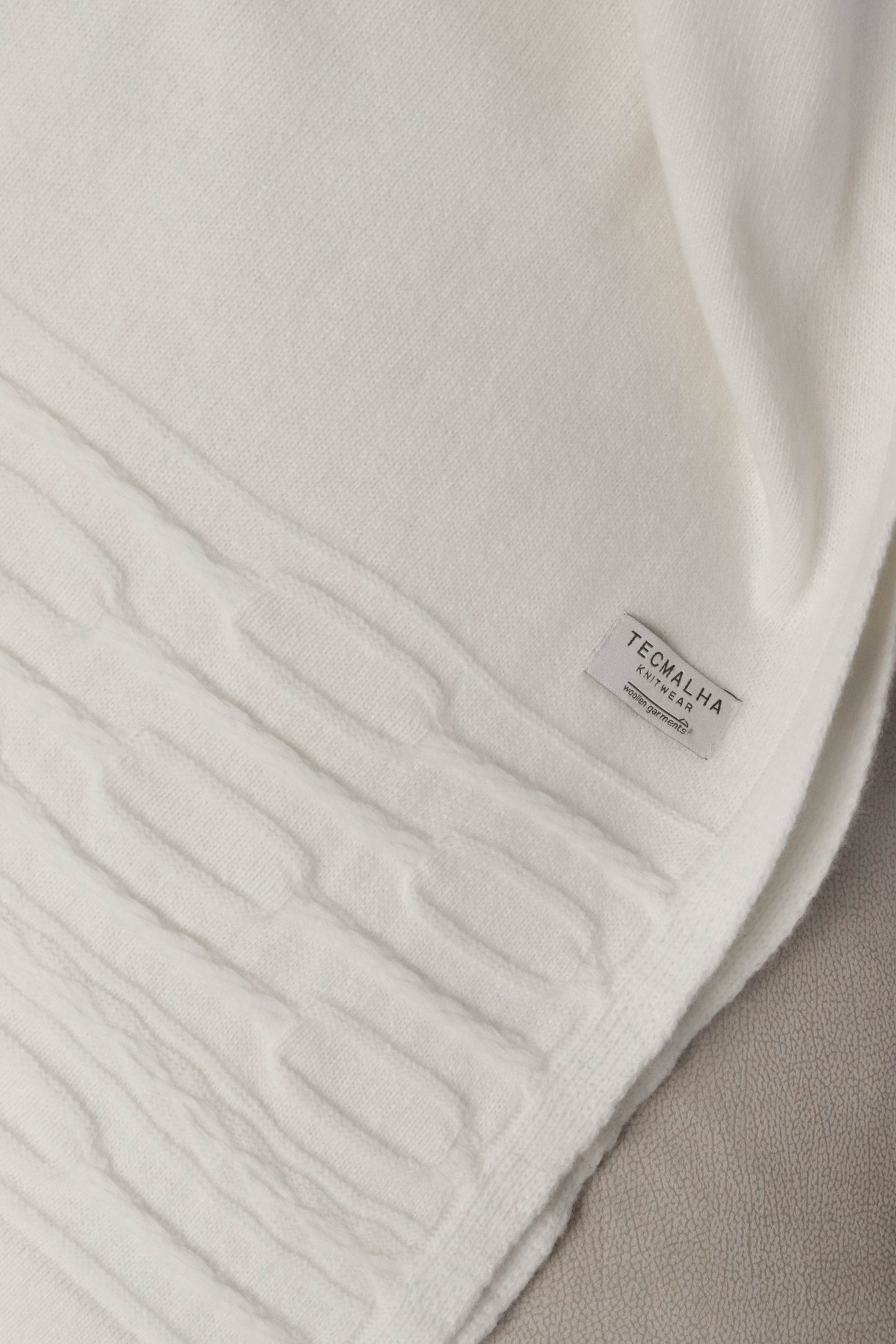 Close-up view of a pearl wool blanket with a raised rope pattern detail on the edges