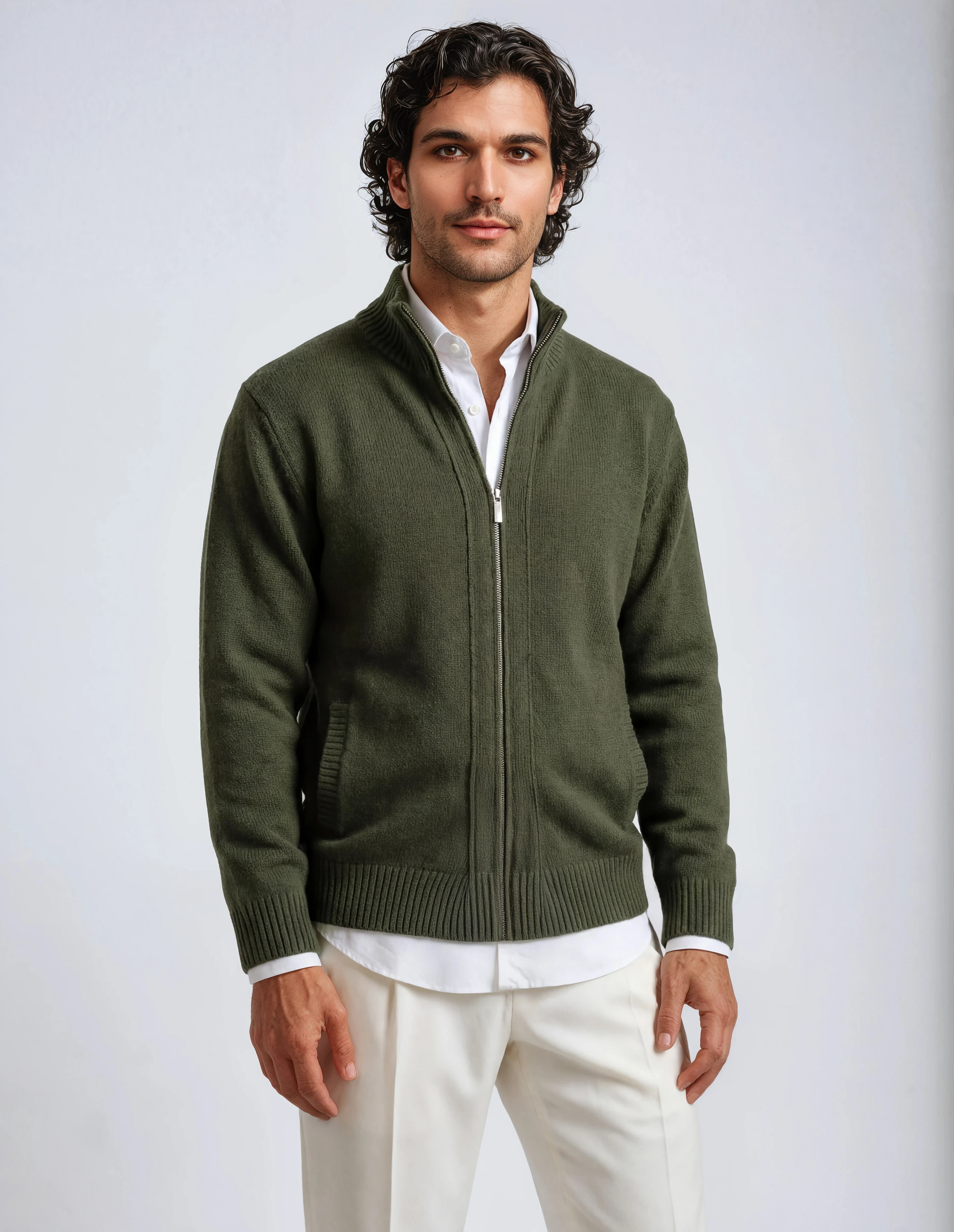 Front view of a man wearing an olive green zip-up knit cardigan over a white collared shirt and cream trousers, featuring ribbed cuffs and hem.
