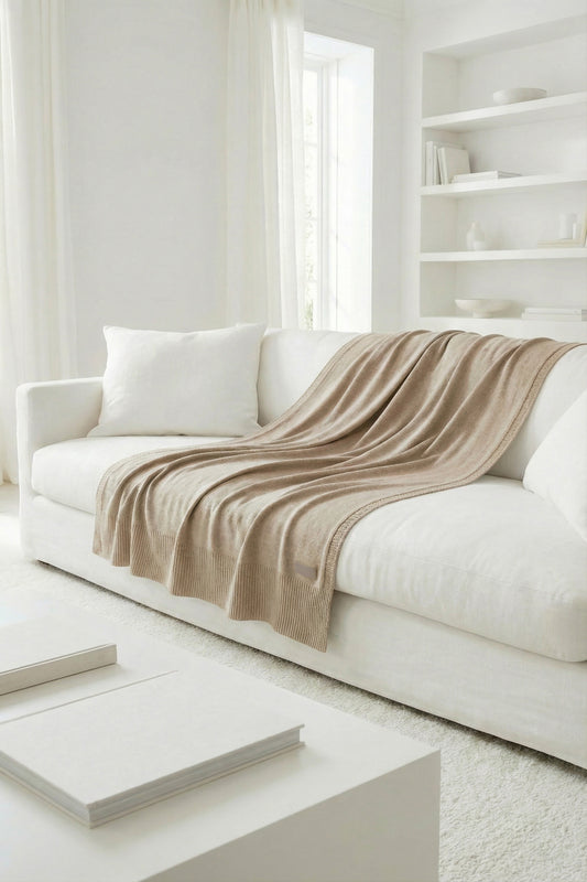 Neutral beige cotton throw with a simple knit design and elegant ribbed edges.