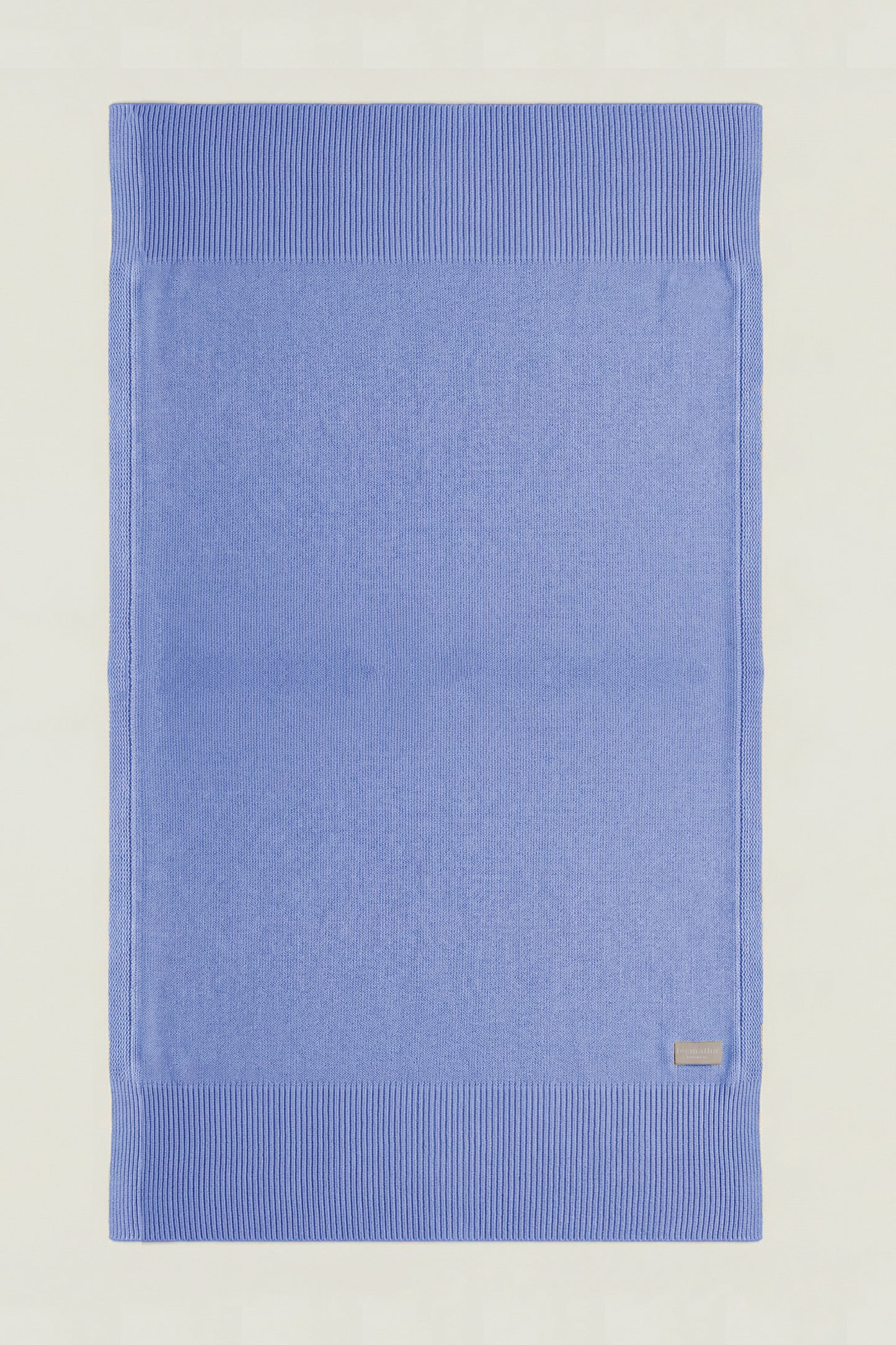 Top-down view of a rectangular cotton knit throw in paste blue, showing the full design and structured borders.