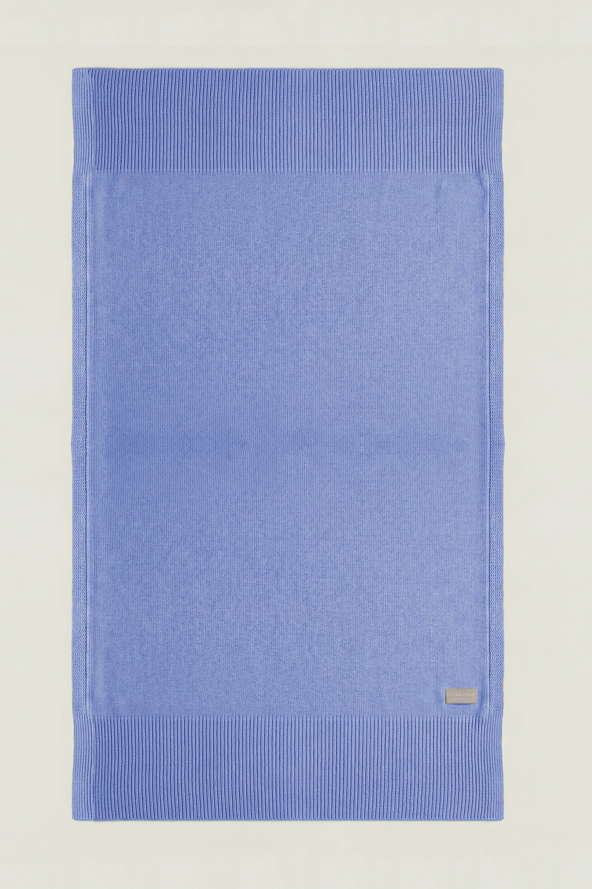 Top-down view of a rectangular cotton knit throw in paste blue, showing the full design and structured borders.