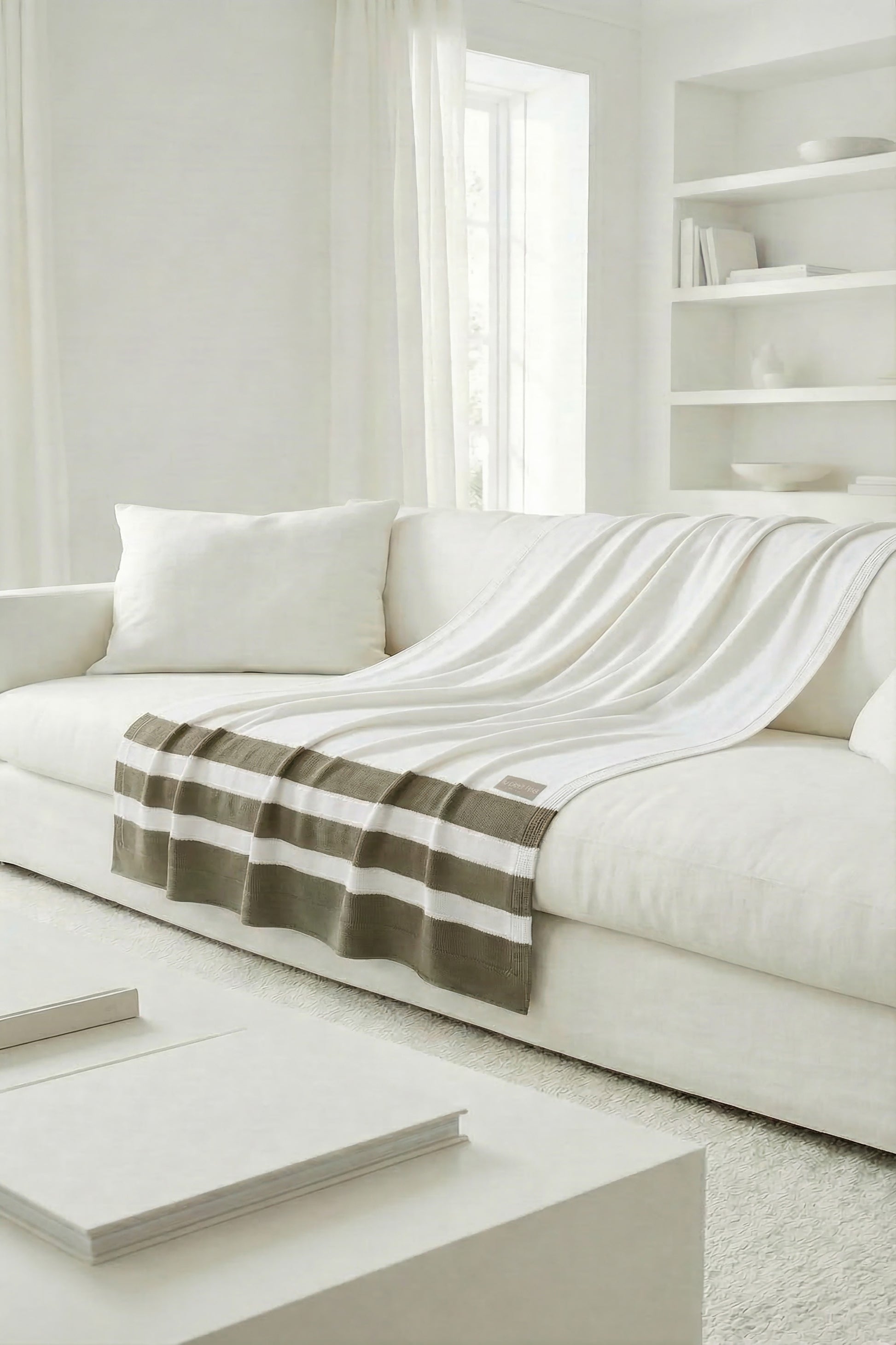 White cotton throw with moss green stripes along the edge, spread out to show the fabric's movement.