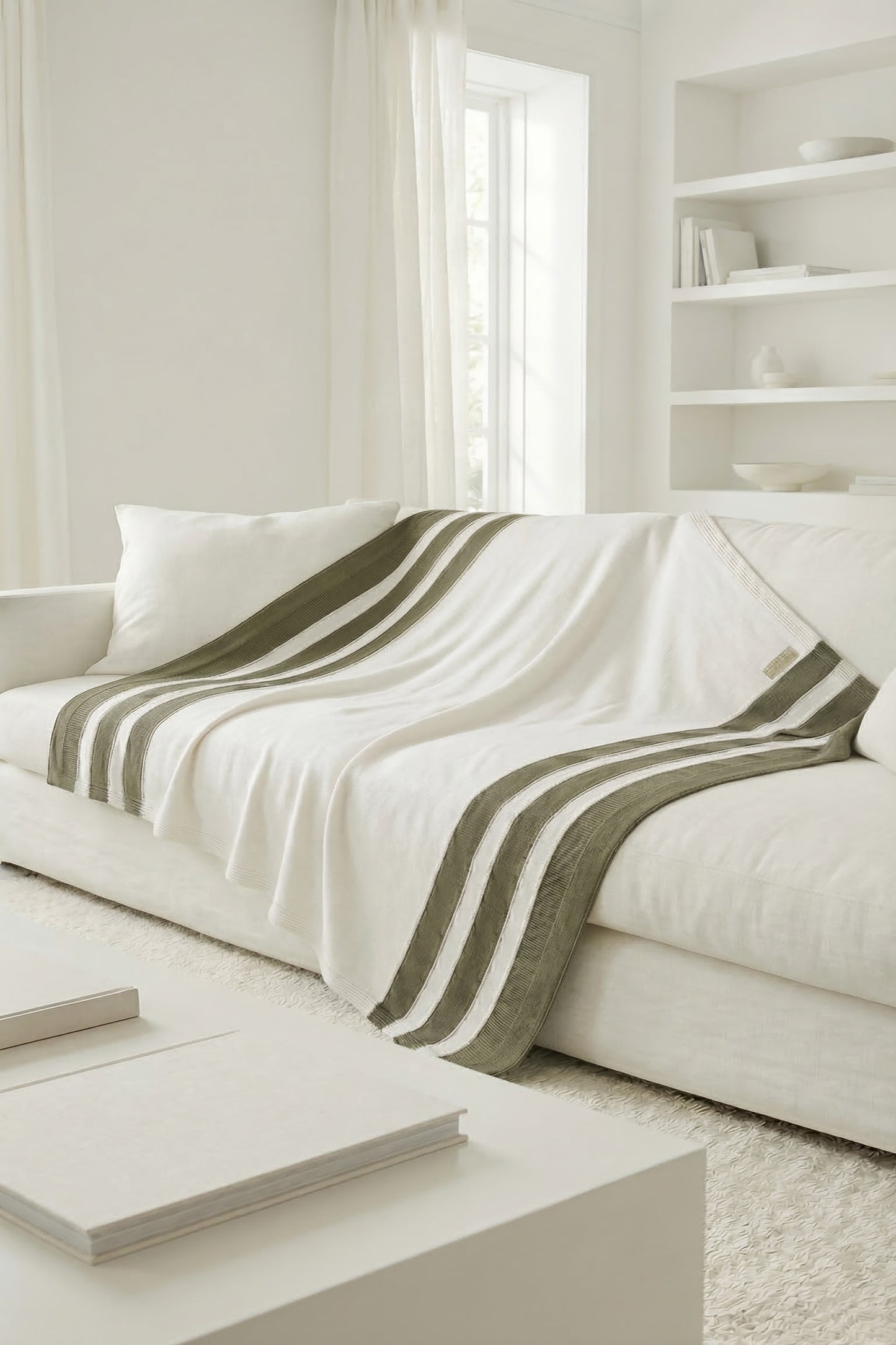 White knit blanket with moss green stripes draped over a sofa, highlighting the natural and earthy tones.