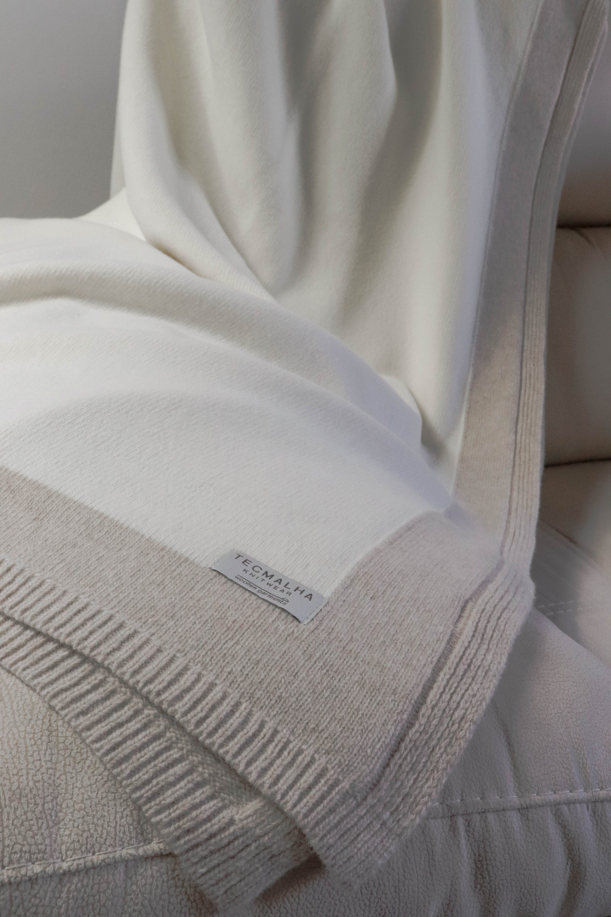 Close-up view of a two-tone wool blanket with a ribbed border, highlighting its soft texture and elegant neutral design.