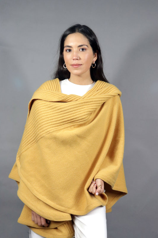 Woman wearing a yellow hooded fall cape, posing against a neutral background, with simple, elegant accessories.